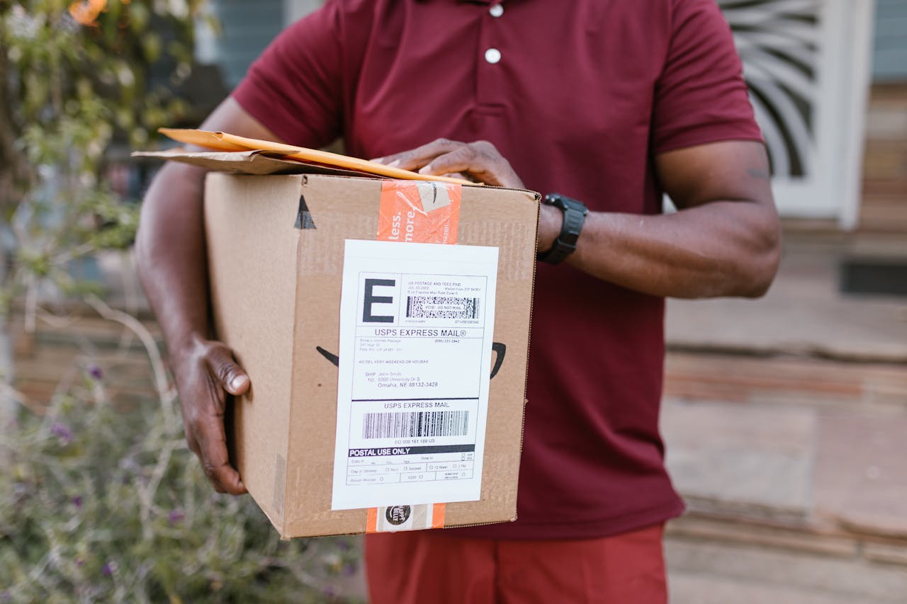 services-04 Close-up of a courier delivering a parcel with USPS express mail label outdoors.