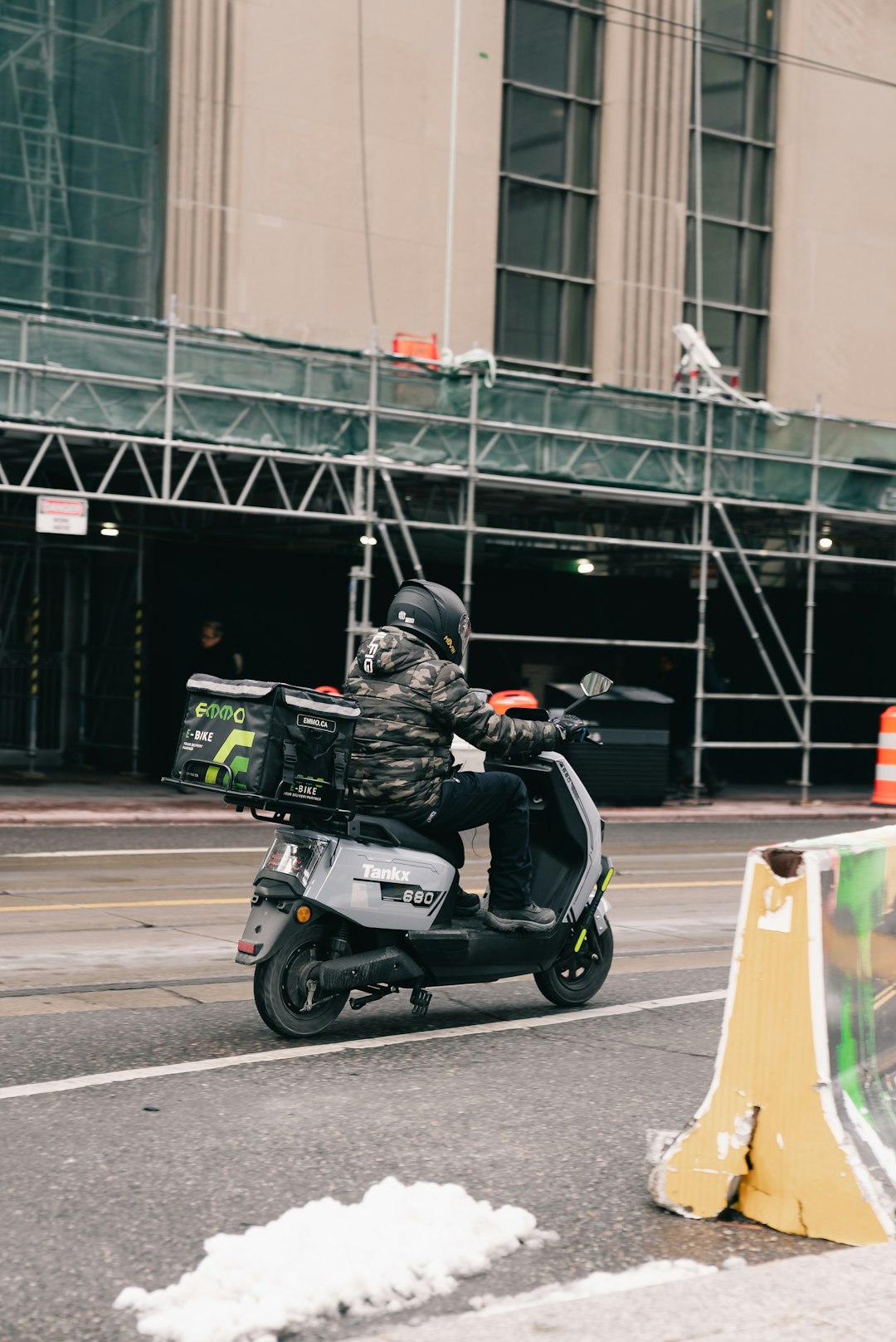 team-02 delivery-person-rides-scooter-past-construction-site-klgcnyuk8qa