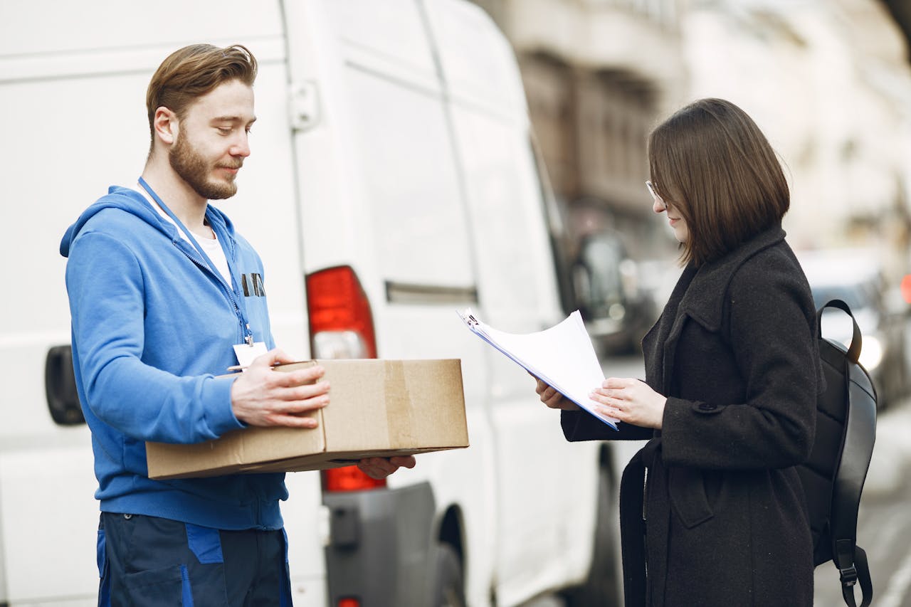 team-04 A courier hands over a package to a woman client on a city street, facilitating delivery service.