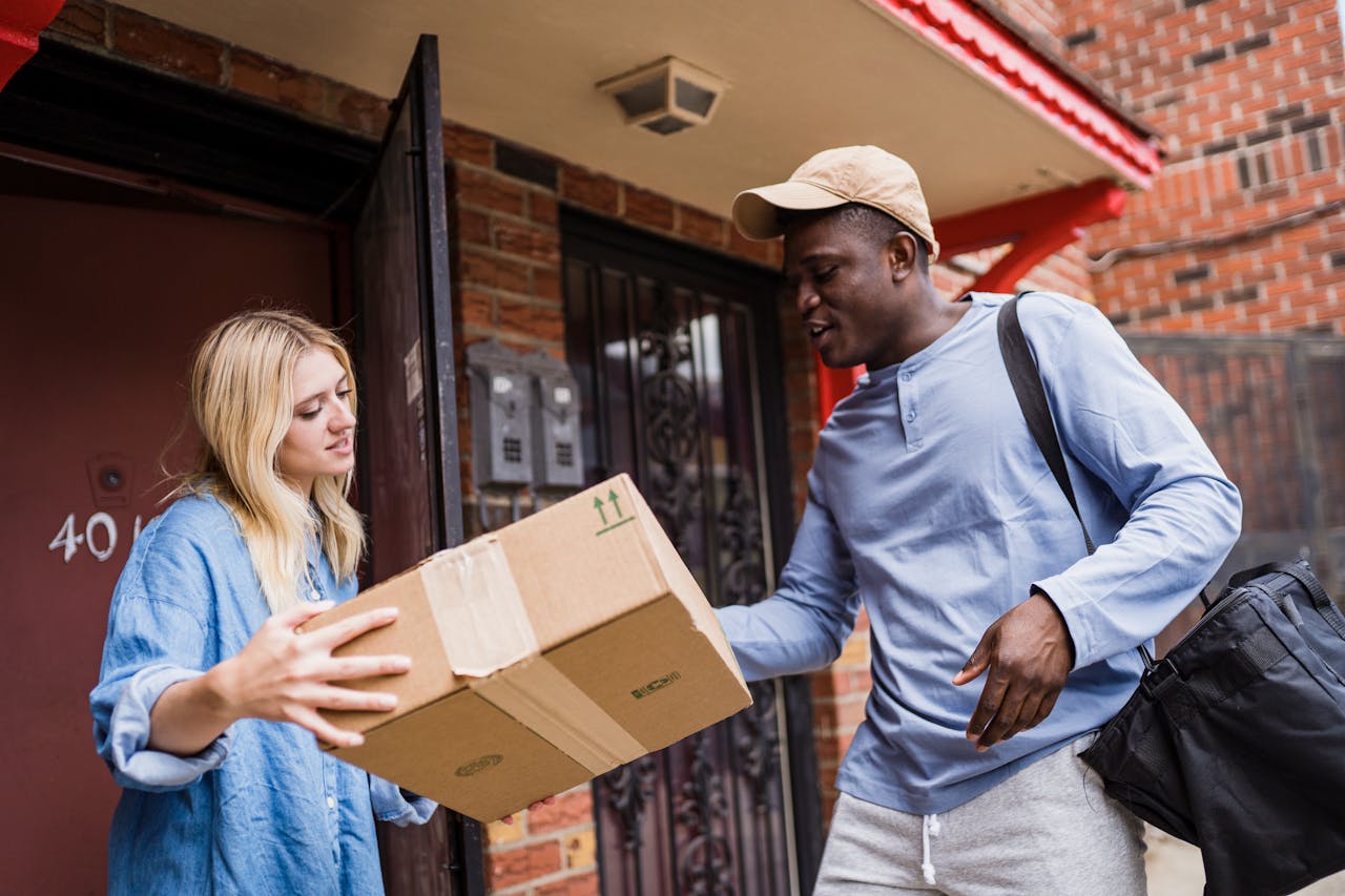 who-we-are A delivery man handing a package to a woman at her doorstep, emphasizing delivery services.